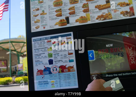Wallingford, CT USA. Mai 2019. Hand mit einem fokussierten Kreditkarte bereit zu einem fast food automatisierte Menü kiosk aufgeladen werden. Stockfoto