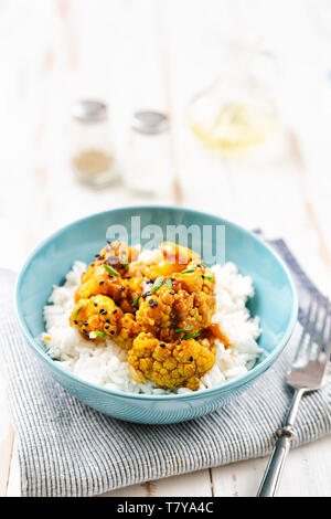 Blumenkohl teriyaki mit Kräutern und Gewürzen mit Reis auf dem Teller, Detailansicht. Vegan Konzept Stockfoto