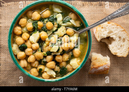 Kichererbsen Suppe mit Spinat und trocken gesalzenen Kabeljau in einem rustikalen Schüssel. Traditionelle spanische Rezeptur in der Heiligen Woche. Stockfoto