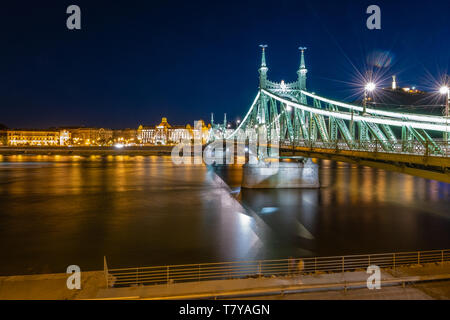 Die Freiheitsbrücke zabadság hid' Blick Richtung Buda mit Gellért Hotel und Hill, Freiheitsstatue, in Budapest Donau Riverside, Nacht. Stockfoto