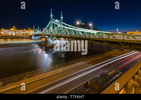 Die Freiheitsbrücke zabadság hid' Blick Richtung Buda mit Gellért Hotel und Hill, Freiheitsstatue, in Budapest Donau Riverside, Nacht. Stockfoto