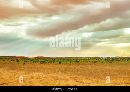 See in Marokko in der Morgendämmerung am Fuße der Wüste Sahara. Die Strahlen der Sonne durch die Wolken. Im Rahmen der Auto- und eine Gruppe von Touristen, die Stockfoto