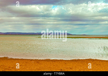 See in Marokko in der Morgendämmerung am Fuße der Wüste Sahara. Die Strahlen der Sonne durch die Wolken. Stockfoto