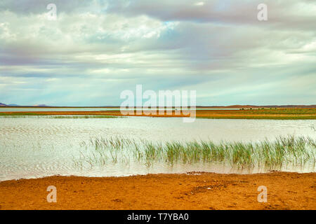 See in Marokko in der Morgendämmerung am Fuße der Wüste Sahara. Die Strahlen der Sonne durch die Wolken. Stockfoto