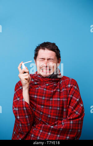 Ein kranker Mann in eine Decke gewickelt wird mit Spray mit Medizin für die Kehle. Stockfoto