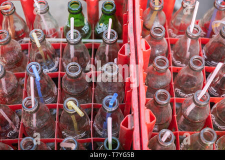 Viele plastik Strohhalme in die Kiste voller leerer Softdrinks (Coca-cola) Flaschen. Stockfoto