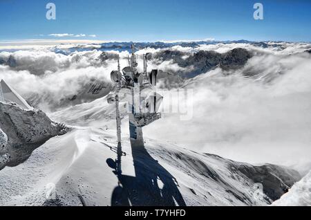 Mast mit Funk- und Funkantennen. Im Hintergrund das winterlich verschneite Alpenpanorama Stockfoto