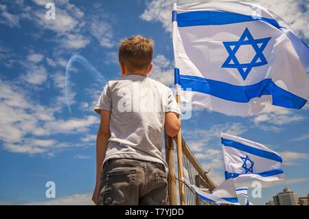 Israelische Kind beobachten die Luftfahrtschau am 71 Israel Tag der Unabhängigkeit mit einer Flagge Israels gegen den blauen Himmel. Stockfoto