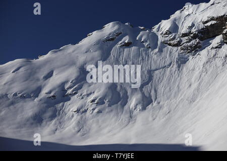 Der Wind hat mit dem Schnee interessante Muster auf die Felswände gezeichnet. Stockfoto