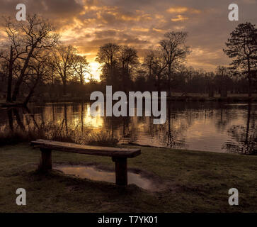 Dunham Massey, Cheshire, England. Sonne über einen noch auf morgen Teich. Sonnenstrahlen brechen die Wolken auf das Wasser widerspiegelt. Stockfoto