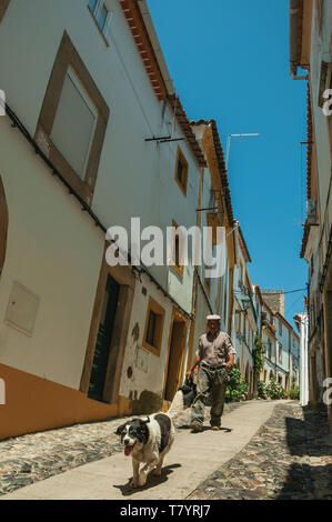 Elder und Hund spazieren auf schmale Gasse mit alten Häusern in Castelo de Vide. Schöne Stadt mit mittelalterlichen Burg an den Portugal Ostgrenze. Stockfoto