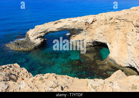 Die 'Liebe Brücke", einem natürlichen Steinbogen, inmitten von seichten türkisblauen Wasser in Ayia Napa, Zypern Stockfoto