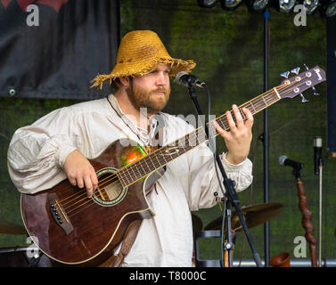 Gifhorn, Deutschland, Mai 4., 2019: Musiker mit einer Ausgefransten alte Strohhut spielen auf eine akustische Gitarre. Stockfoto