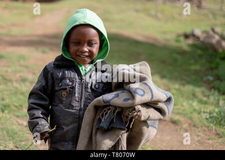 Junge Junge, die eine Decke in einem kleinen Dorf in der Nähe von mokhotlong im Nordosten Lesotho, Afrika. Stockfoto
