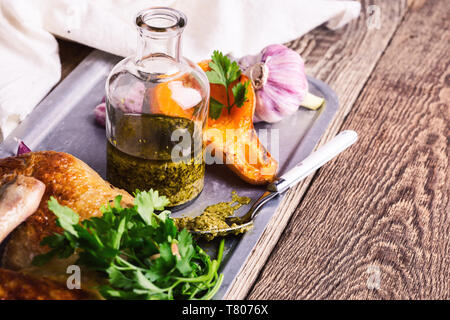 Pesto, gebratene Hähnchenschenkel, Kürbis und frische Petersilie auf rustikalen Holztisch, Fleisch und Gemüse braten Abendessen Stockfoto