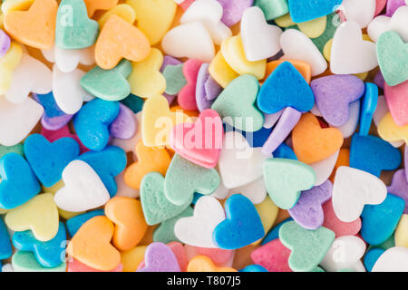 Happy Valentinstag. Haufen von kleinen Süßigkeiten Herzen verschiedener Farben. Ein rotes Herz in der Mitte. Konzept der Liebe und Februar Urlaub. Einsamkeit ein Stockfoto