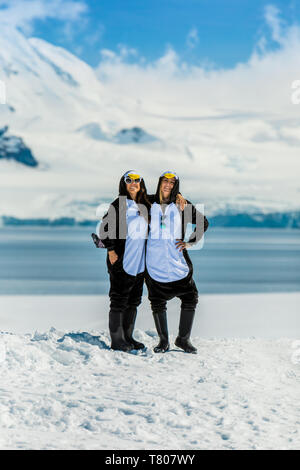 Zwei amerikanische Frauen Touristen in Penguin Onesies an einem sonnigen Tag, auf den Gletschern Posing, Antarktis, Polargebiete Stockfoto