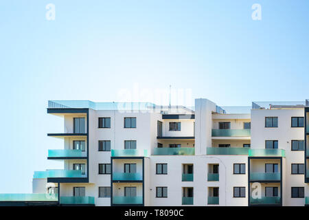 Neu gebauten Wohnungen Gebäude auf einem strahlend blauen Himmel, mit Platz für Text oben. Den oberen Teil des ein weißes Gebäude mit blauen Glas Balkone und zuvorzukommen. Stockfoto