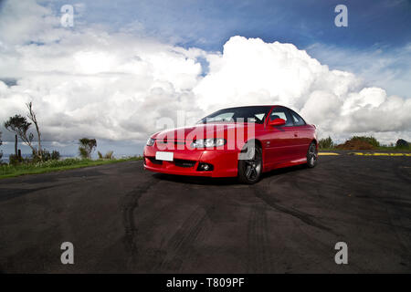 Red Holden Monaro HSV Coupe II 2003 GTO, Opel, Pontiac GTO, Chevrolet Lumina Coupé. Scenic Drive, Waitakere Ranges, Pukematekeo Blick auf Waitemata Stockfoto