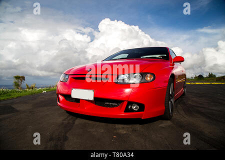 Red Holden Monaro HSV Coupe II 2003 GTO, Opel, Pontiac GTO, Chevrolet Lumina Coupé. Scenic Drive, Waitakere Ranges, Pukematekeo Blick auf Waitemata Stockfoto