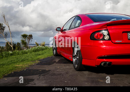 Red Holden Monaro HSV Coupe II 2003 GTO, Opel, Pontiac GTO, Chevrolet Lumina Coupé. Scenic Drive, Waitakere Ranges, Pukematekeo. Glänzend Sportwagen. Stockfoto