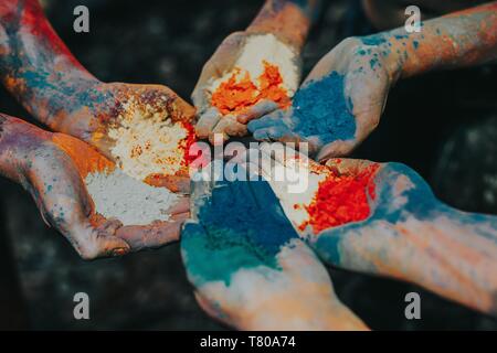 Sechs Hände nebeneinander halten verschiedene Farben in einer Farbe festival - Indische Bräuche und Traditionen - teilweise mit Blick auf die jungen Menschen ho Stockfoto