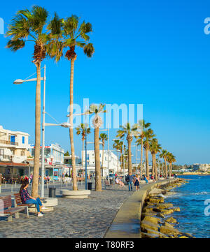 PAPHOS, Zypern - 13. FEBRUAR 2019: Menschen auf Paphos Promenade bei Sonnenuntergang. Paphos ist die berühmte touristische Destination in Zypern Stockfoto