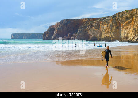 SAGRES, PORTUGAL - Oktober 30, 2018: Junger Mann zu Fuß vom Sandstrand mit Surfbrett. Die Algarve ist eine berühmte Surfen in Portugal Stockfoto