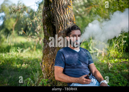 Stilvolle brutalen Mann rauchen eine elektronische Zigarette outdoorr. Nicht rauchen. Stockfoto