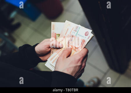 Ein Mann hält Rubel und Dollar in der Hand, ein Geschäftsmann hat Geld in der Hand Stockfoto