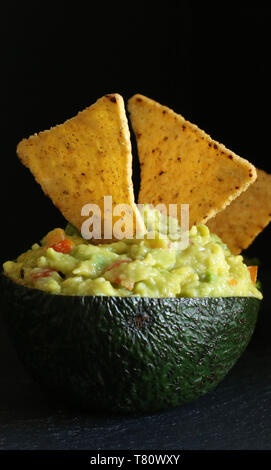 Guacamole mit Tortillas auf schwarzem Hintergrund Stockfoto