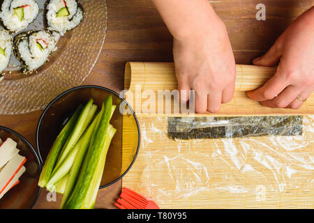 Eine Frau Koch bereitet Sushi in der Küche und wickelt einen Brief an die Nori in der Rolle 2019 Stockfoto