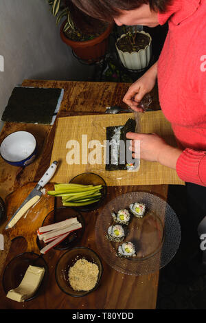 Eine Frau Koch bereitet Sushi in der Küche und wickelt einen Brief an die Nori in der Rolle 2019 Stockfoto