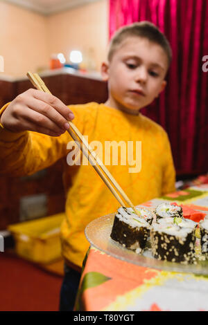 Die jugendlich Junge nimmt das Sushi Roll der Platte 2019 Essen Stockfoto