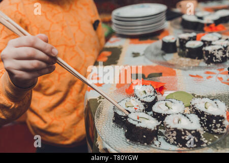 Die jugendlich Junge nimmt das Sushi Roll der Platte 2019 Essen Stockfoto