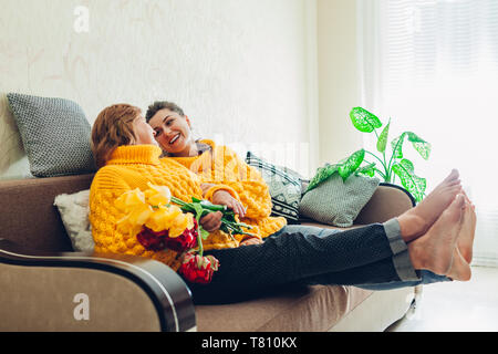 Ältere Mutter und ihre erwachsene Tochter sitzen auf der Couch und zu Hause lacht. Muttertag Konzept. Stockfoto