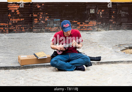 Junger Mann Straßenmusik auf einer Straße in Sevilla spielen eine Ukulele Stockfoto