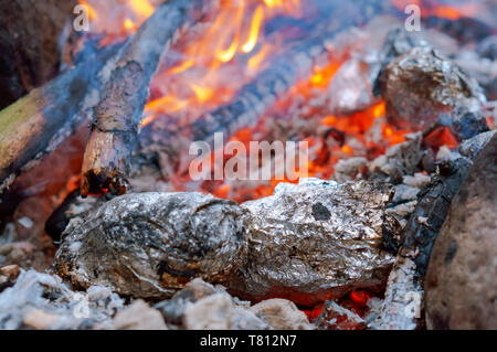 Gebackene Kartoffeln, Gemüse in Folie gebacken auf Feuer Stockfoto