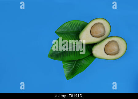 Reife Frucht grün Avocado und eine Hälfte auf einem blauen Hintergrund Stockfoto