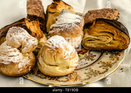 Stücke von verschiedenen Kuchen mit Eclairs und traditionellen armenischen Cookies' Gata' und Baklava aus Blätterteig auf einem vintage Porzellan Platte Stockfoto