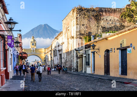 Antigua, Guatemala - April 14, 2019: Straße mit Santa Catalina Arch, Ruinen & Agua Vulkan hinter in der kolonialen Stadt und UNESCO-Weltkulturerbe. Stockfoto