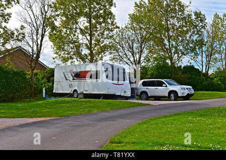 Modernes Auto und Caravan Outfit auf einem komplett gewartet pitch Beverley Park Holiday Park in Torquay, Devon. Hintergrund der Bäume in Blätter kommen. Stockfoto