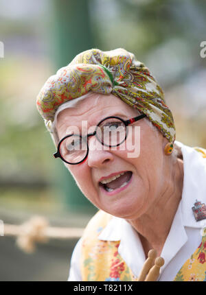 Close-up front view Portrait von isolierten kaukasische Frau mit Kopftuch & Overalls als authentische vintage Hausfrau, Putzfrau Frau Mop in 1940 WWII Ereignis. Stockfoto