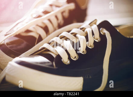 Schwarz classic sports Schuhe mit Schnürsenkel aufgebunden liegen in der Flur von Rosa morgen Sonnenlicht beleuchtet. Stockfoto