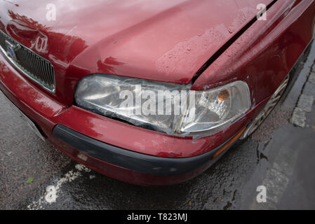 Fahrzeug zum Absturz bringen. Defekten Scheinwerfer und beschädigte Stoßfänger auf einem alten roten Auto. Auto Crash Hintergrund. Stockfoto