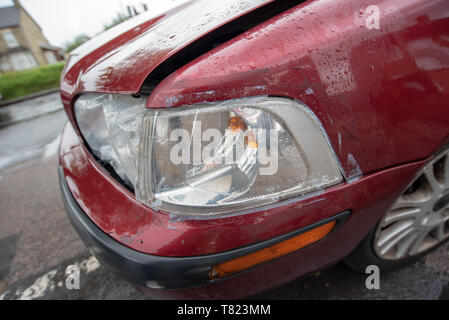 Fahrzeug zum Absturz bringen. Defekten Scheinwerfer und beschädigte Stoßfänger auf einem alten roten Auto. Auto Crash Hintergrund. Stockfoto