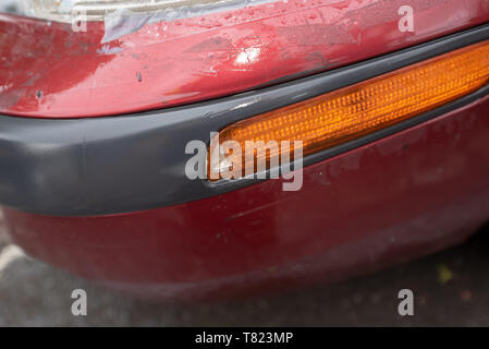 Fahrzeug zum Absturz bringen. Defekten Scheinwerfer und beschädigte Stoßfänger auf einem alten roten Auto. Auto Crash Hintergrund. Stockfoto