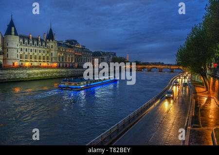 Ein Boot auf dem Fluss Seine in der Dämmerung, in Paris, Frankreich. Auto leuchtet die Straße neben dem Fluss beleuchten. Stockfoto