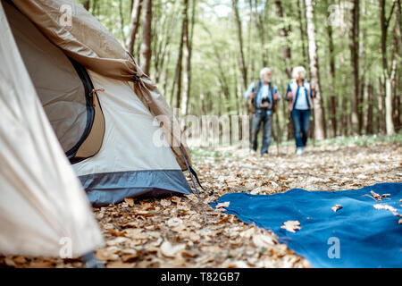 Senior Paar in der Nähe des Campingplatz im Wald. Zelt im Fokus. Konzept eines aktiven Lebensstils auf Ruhestand Stockfoto