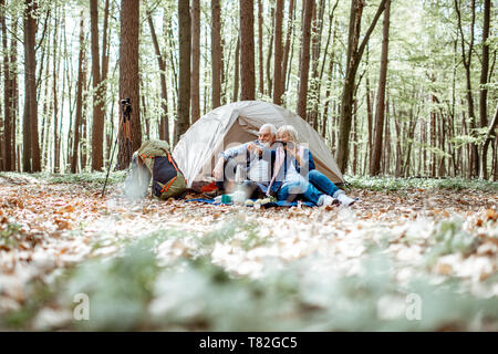 Senior Paar auf dem Campingplatz im Wald sitzen, weite Aussicht auf die Wälder Stockfoto